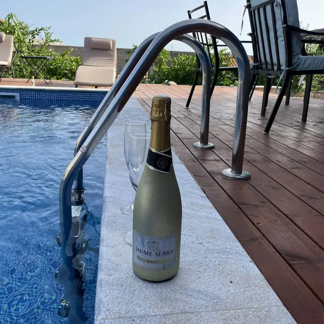 Garrafa de espumante junto à escada da piscina ao entardecer