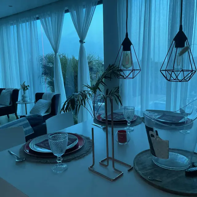 Sala de estar com poltronas voltadas para a piscina ao anoitecer